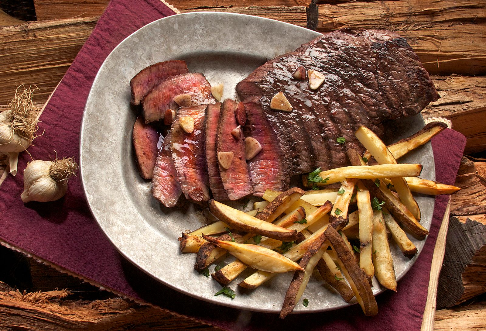 Pièce de bœuf tranchée sur plat de service, frites maison