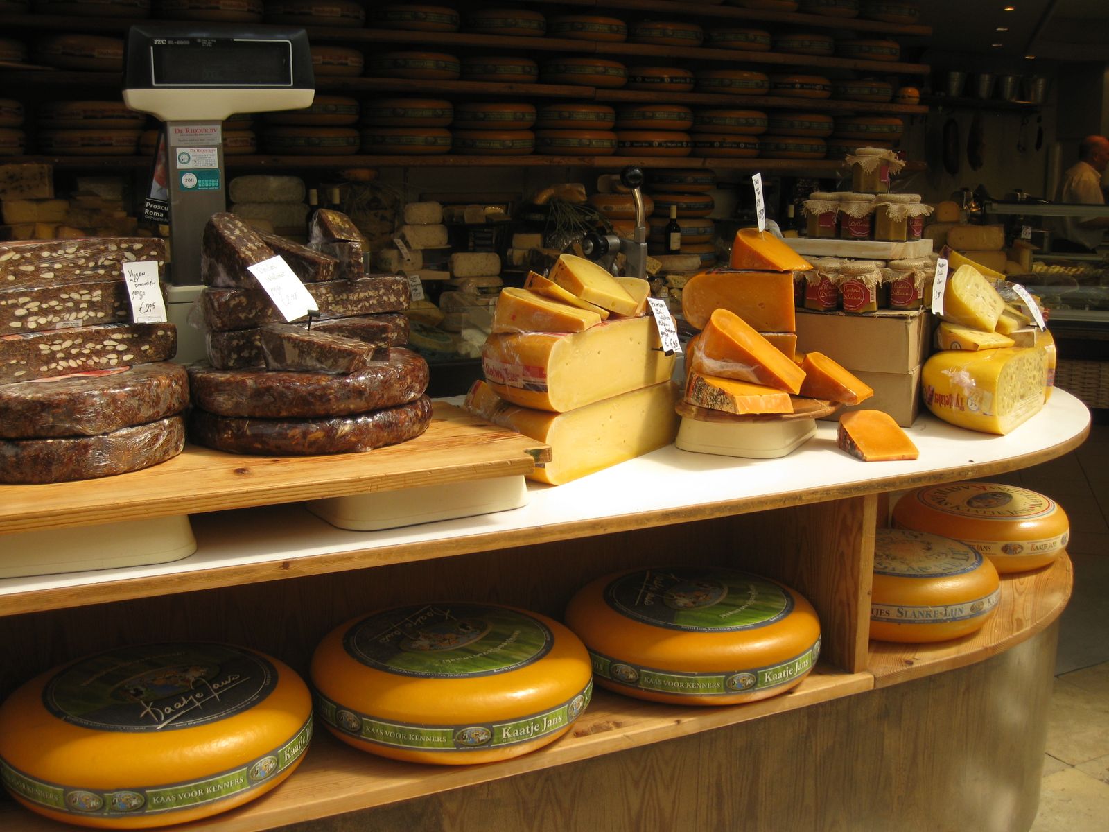 Des tommes entières et des fromages affinés rangés sur les étagères de la fromagerie