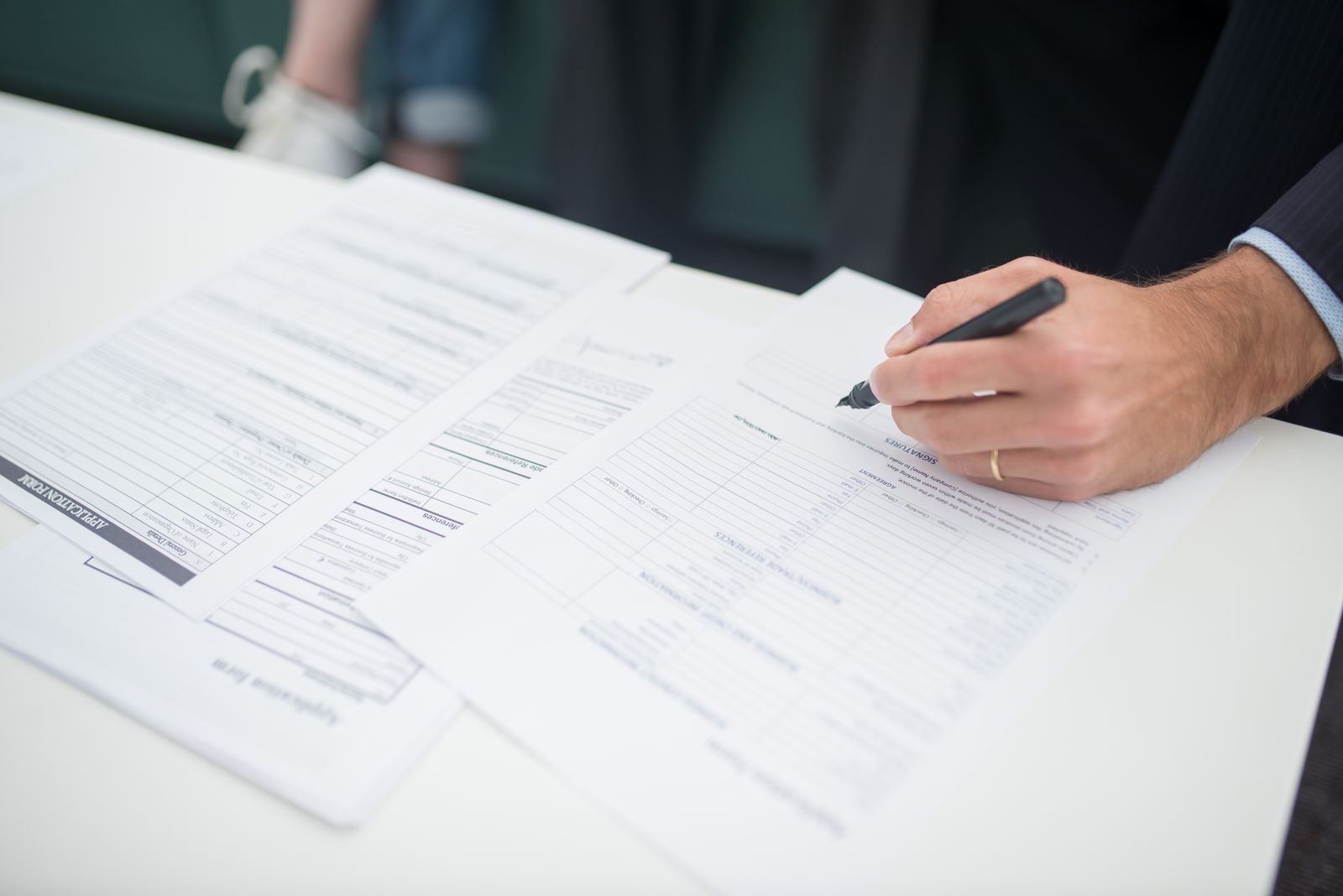 Une main annote les pages d'une délibération posée sur la table du conseil