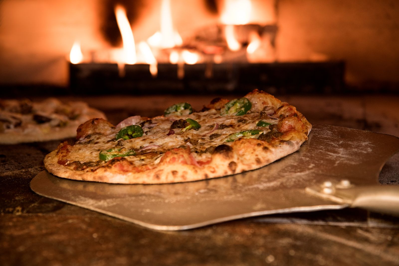La pelle glisse une pizza dans le four à bois