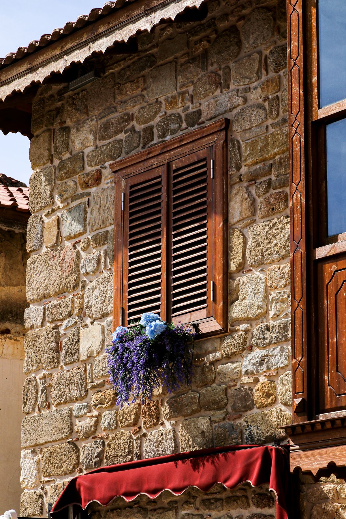 Façade en pierre d'une maison d'hôtes gasconne, volets et glycine