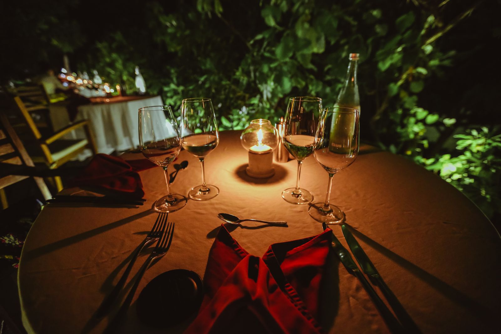 Table d'hôtes dressée le soir, bougies et verres sous la treille