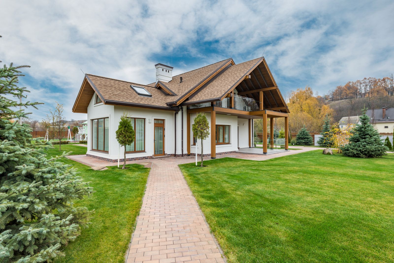 Jardin créé par un paysagiste, allée pavée et maison en fond