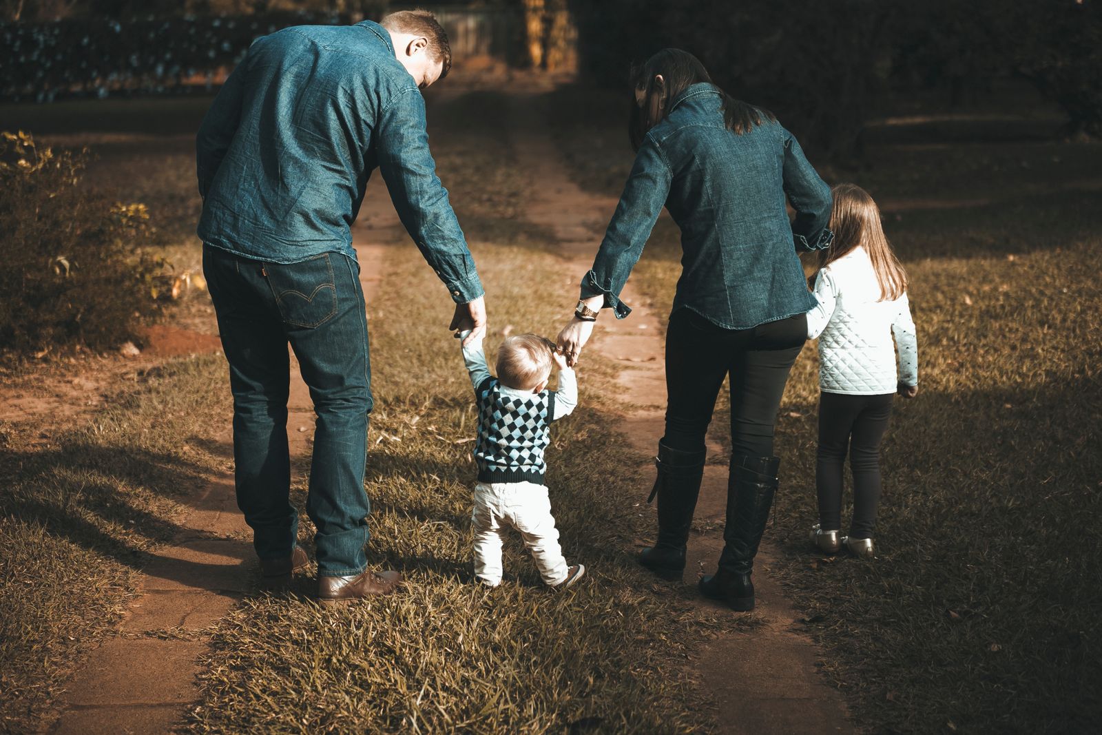 Parents et enfant marchant main dans la main sur un chemin au soleil couchant